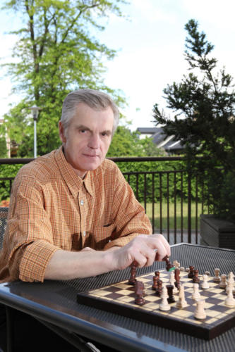 zdjęcie mieszkaniec siedzący na tarasie domu grający w szachy.