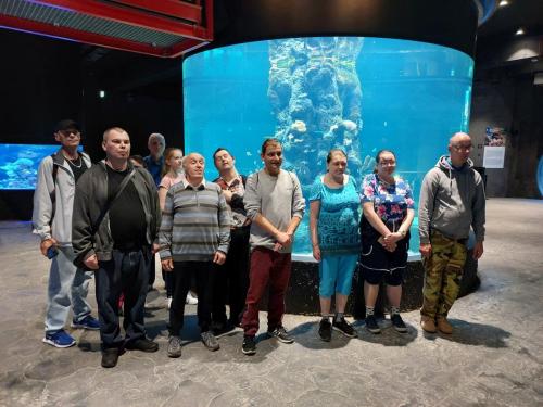 grupa ludzi stoi przy dużym akwarium 